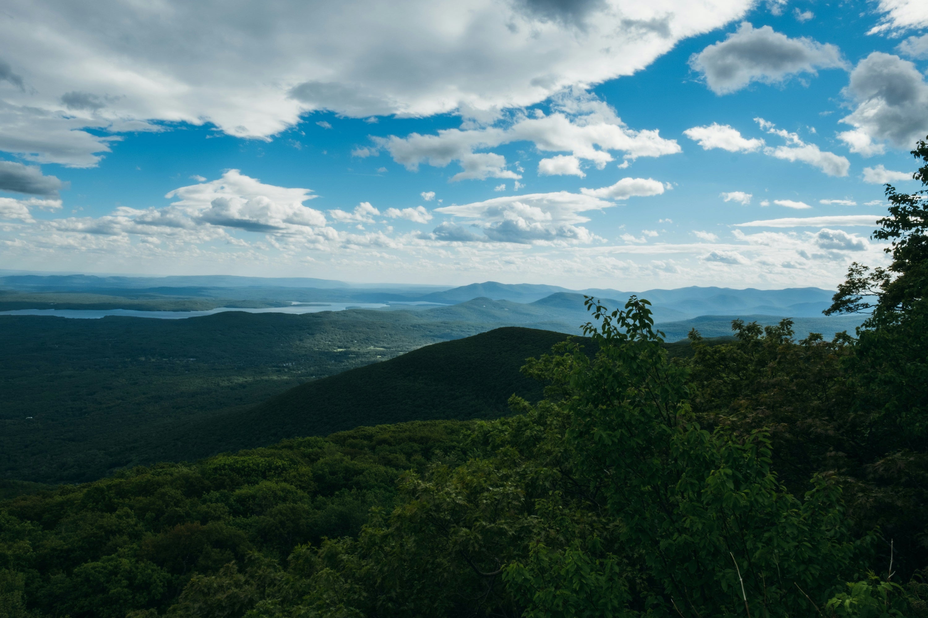 blue sky with white puffy clouds and aerial view of the Catskill Mountains in summer season