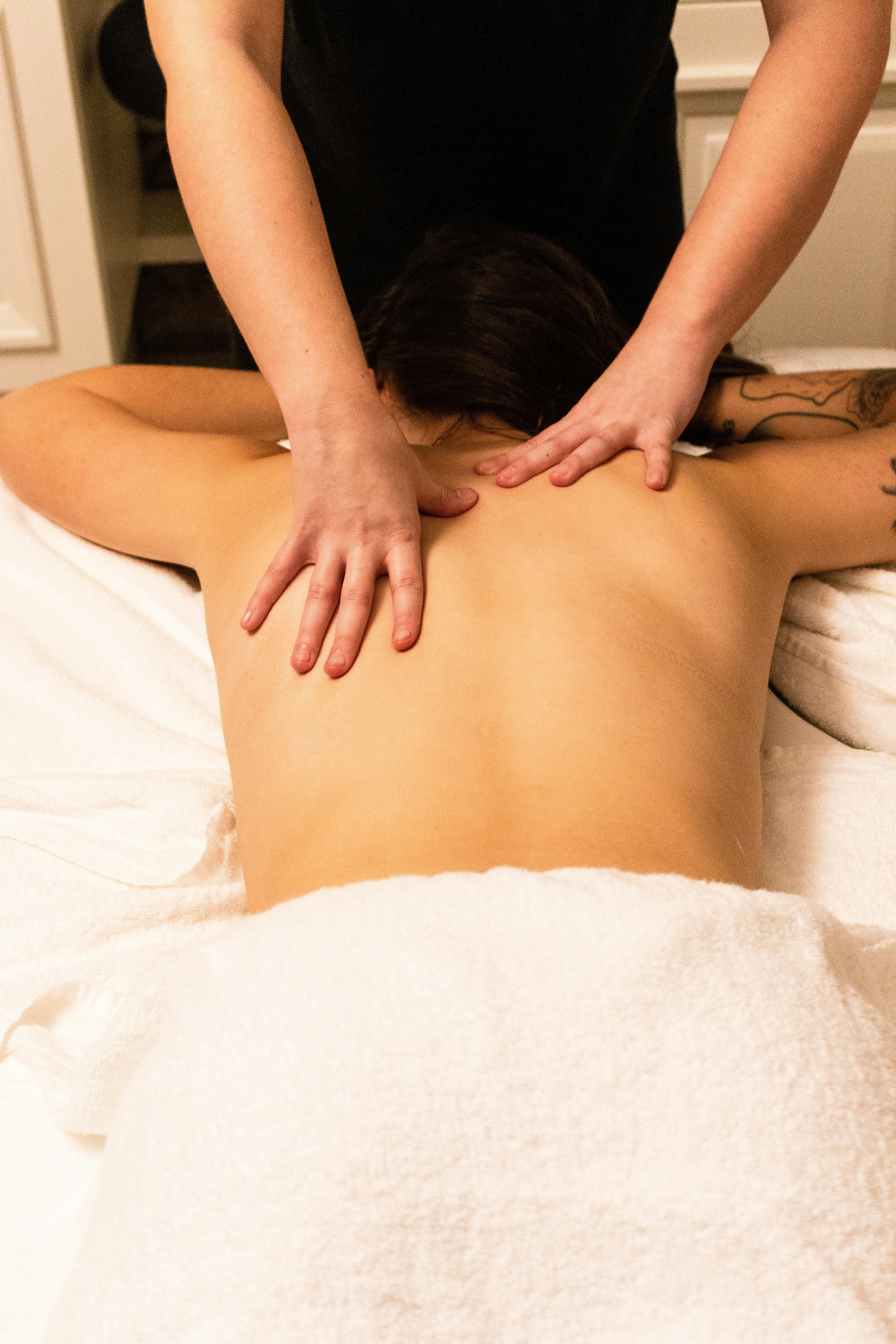 massage therapist giving back massage to woman