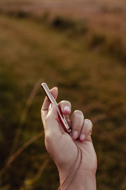 Rose Gold Personal Vibrator Necklace in hand_pleasure_nature