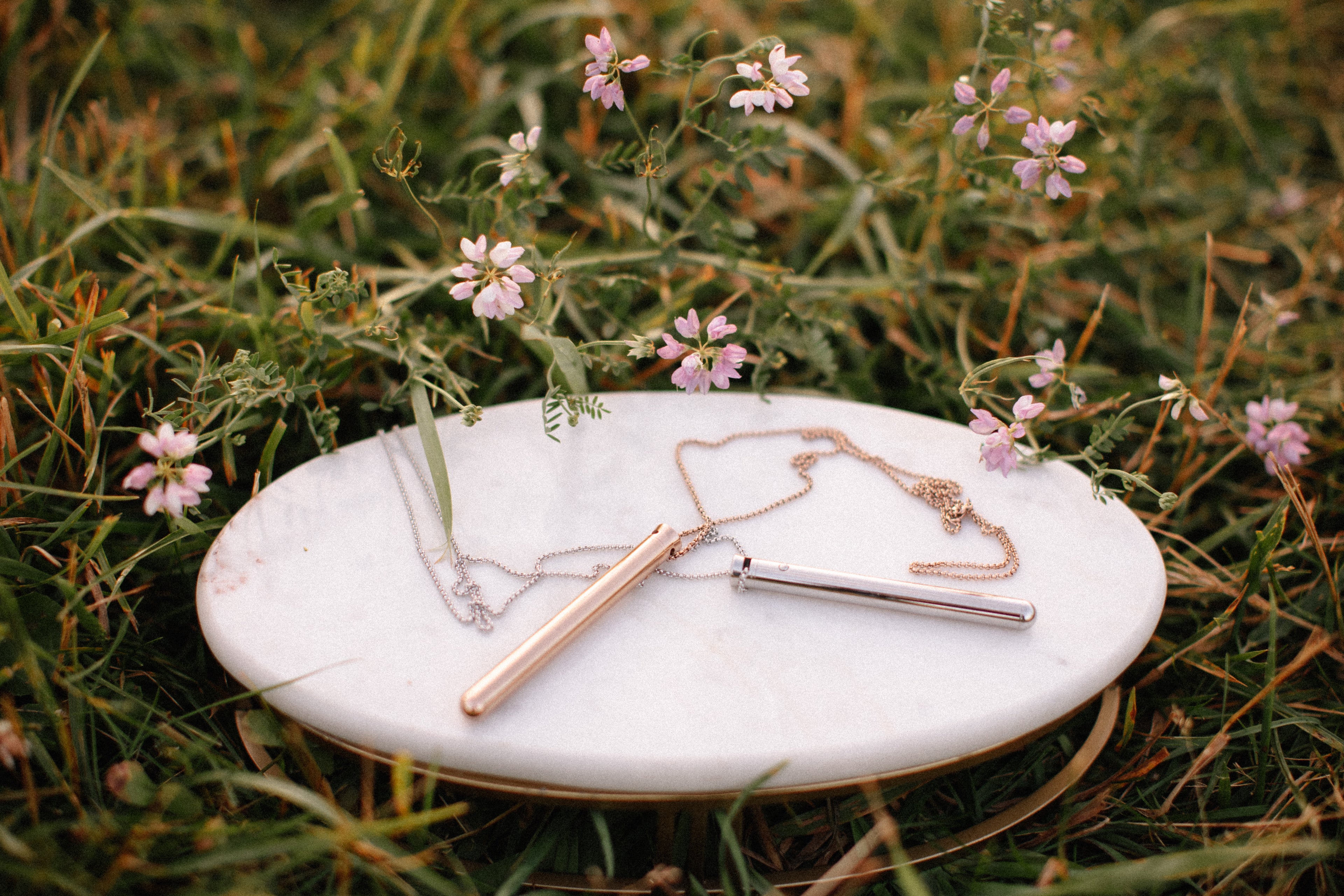 silver and gold vibrator necklaces in natural setting